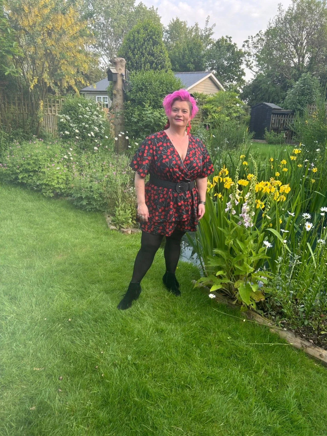 Belinda Warburton standing in a garden surrounded by flowers.